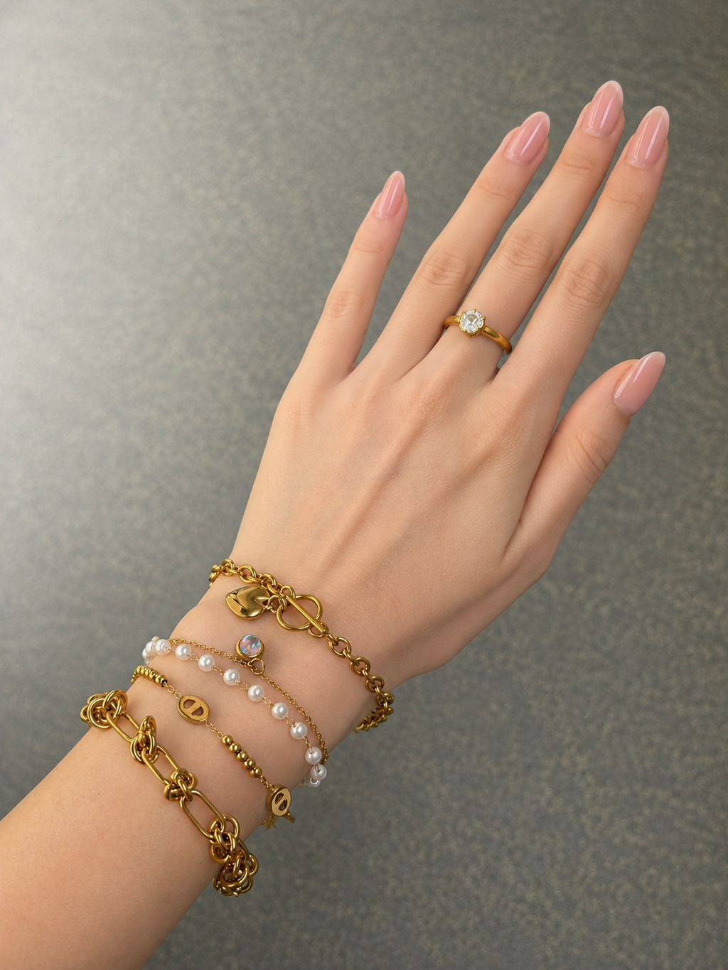 Layered gold-tone bracelets worn on hand with Knot Link bracelet in front