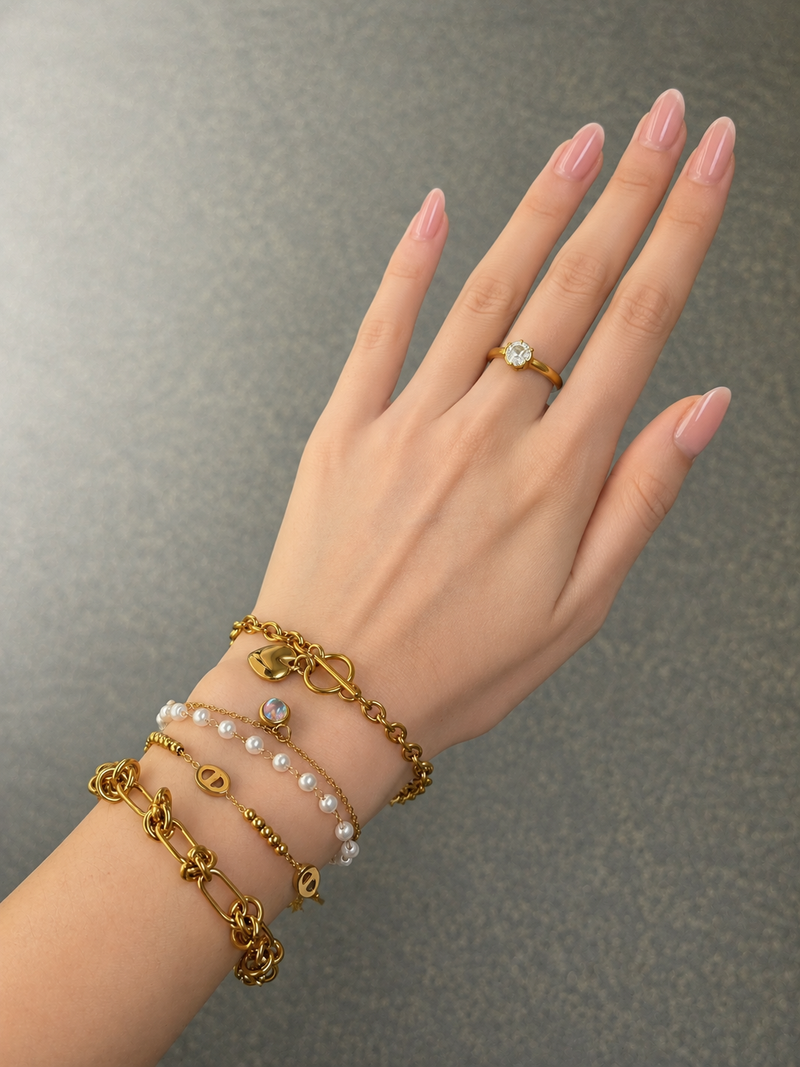 Layered gold-tone bracelets worn on hand with Knot Link bracelet in front