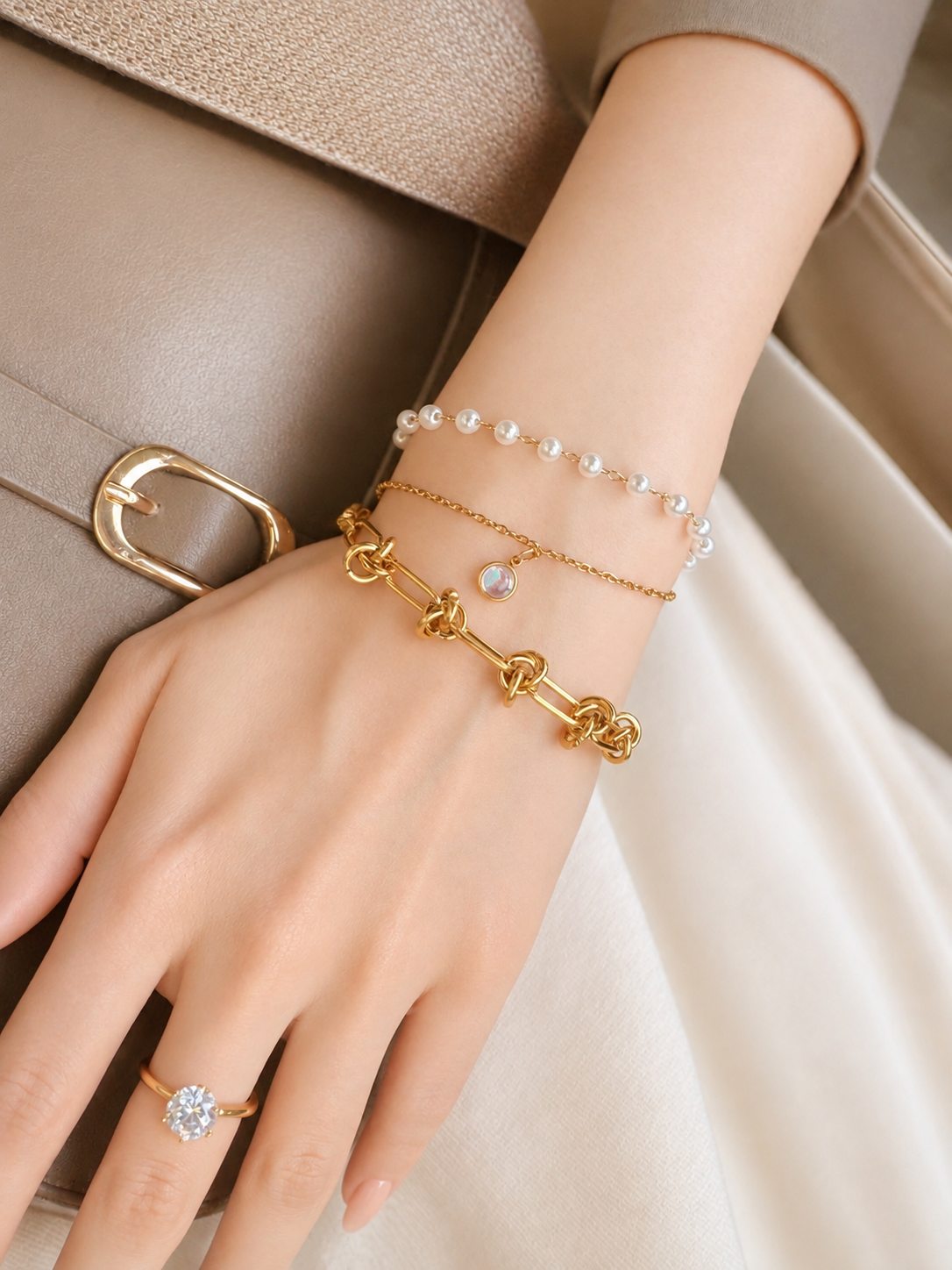 Faux-pearl and gold-tone charm bracelet layered on wrist