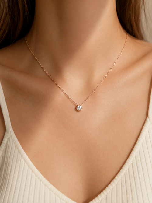 Rose-gold-tone moissanite bezel necklace worn at the collarbone