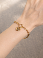 Gold-tone heart charm bracelet with toggle clasp worn on wrist