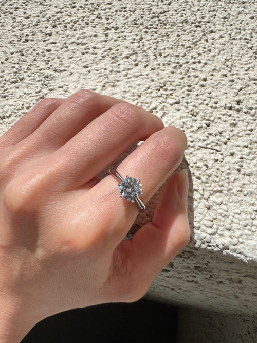 Silver-tone cubic zirconia solitaire ring worn on hand in sunlight