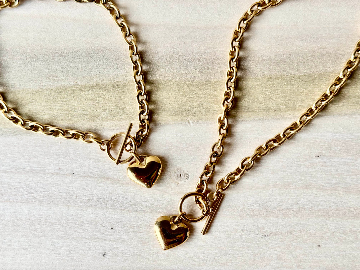 Gold-tone heart necklace and bracelet set arranged on cream fabric