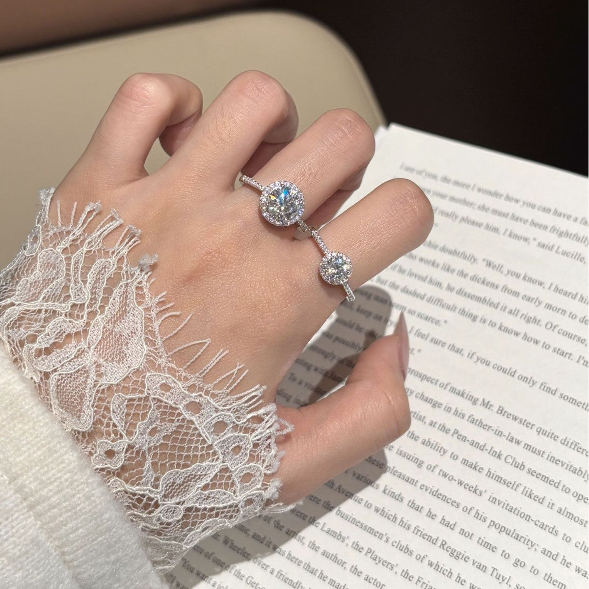 The Halo moissanite ring worn on a hand with a lace cuff