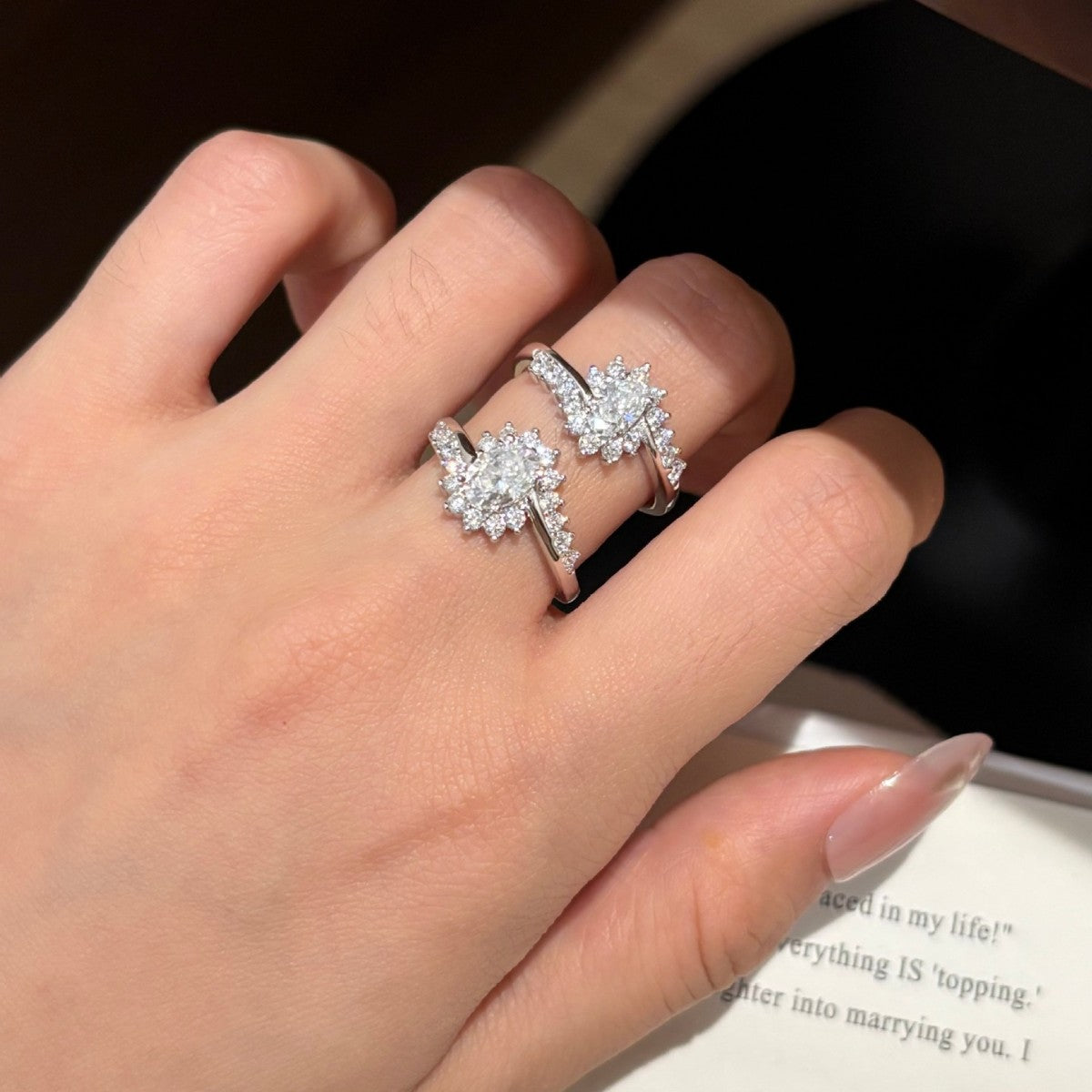 Two Sunburst moissanite rings worn on one hand, oval stones with radiating smaller stones