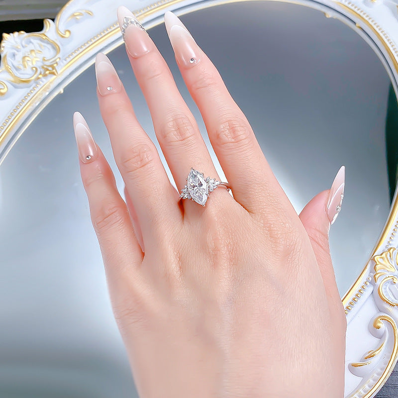 Marquise moissanite ring on the ring finger, hand laid flat over a mirror