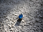 Deep blue pear-cut cubic zirconia pendant photographed on textured stone