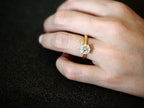 Gold-tone cubic zirconia solitaire ring worn on hand