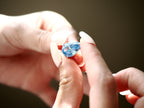 Light blue pear-cut cubic zirconia pendant held between fingers