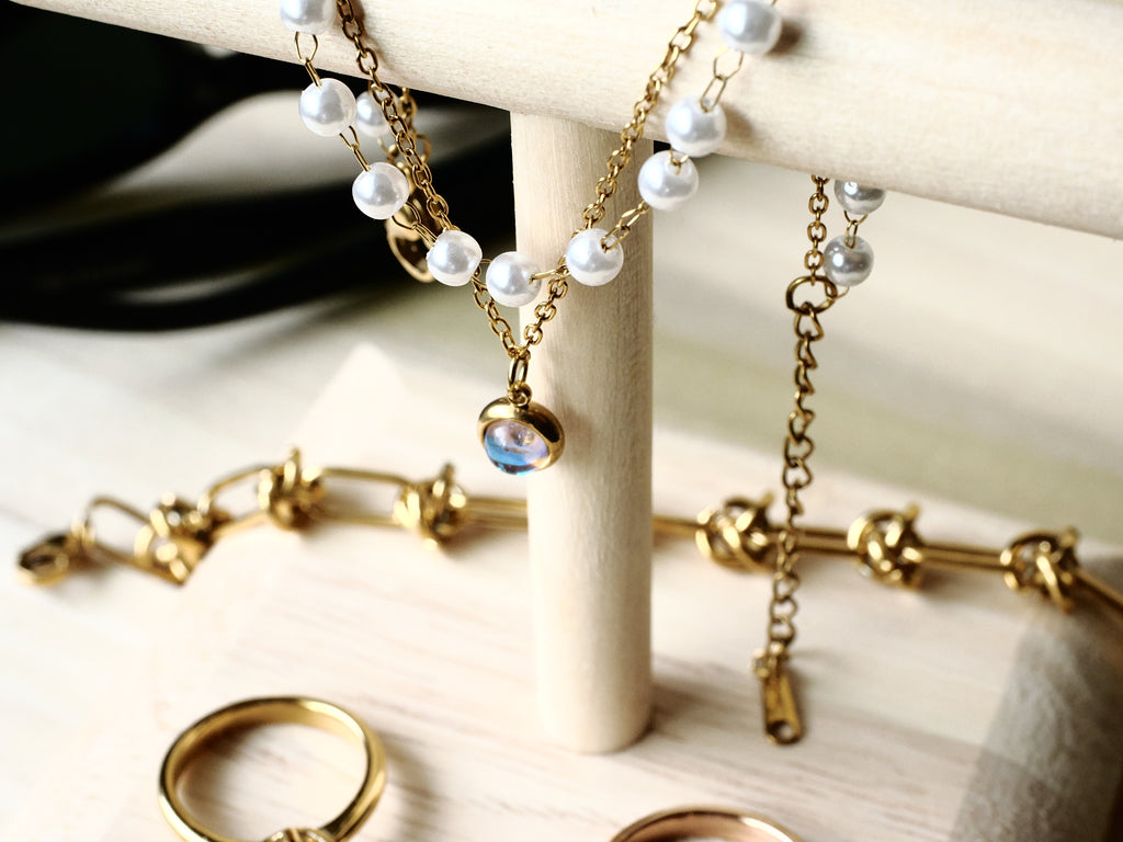 Faux-pearl and gold-tone charm bracelet displayed with other jewelry