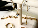 Faux-pearl and gold-tone charm bracelet displayed with other jewelry