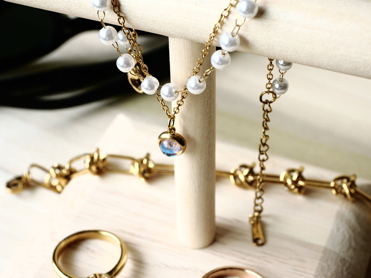 Faux-pearl and gold-tone charm bracelet displayed with other jewelry