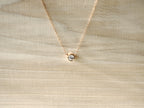 Rose-gold-tone necklace with round bezel-set stone on cream fabric