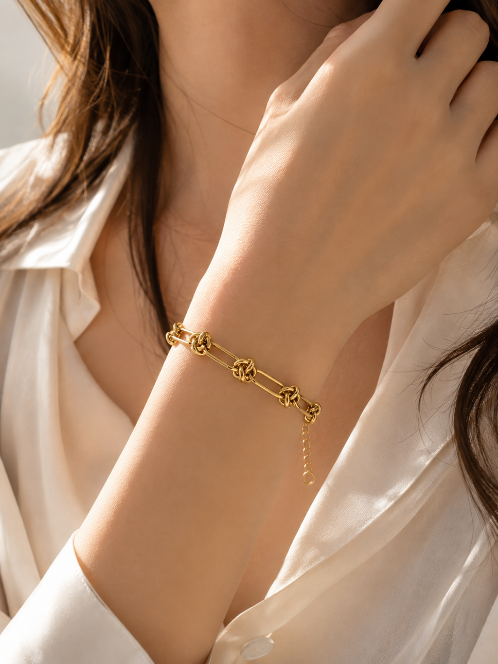 Gold-tone Knot Link bracelet worn on wrist with white blouse